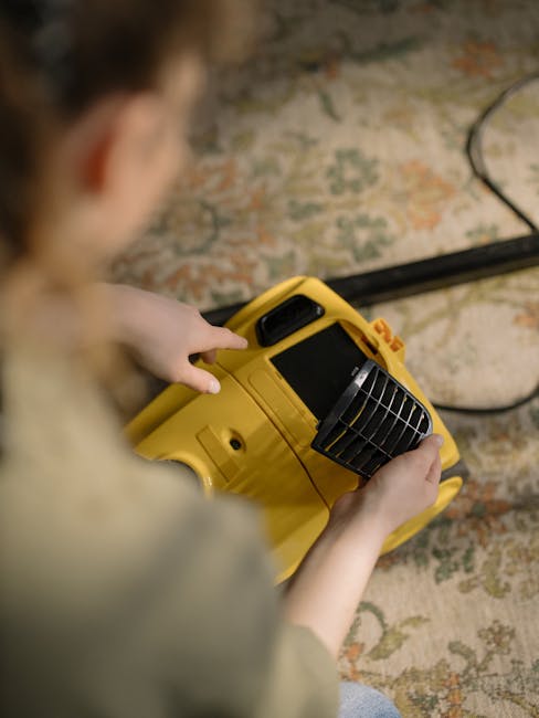 A professional cleaner from Cleaners SW16, dressed in full protective gear including a white suit, gloves, mask, and shoe covers, performs deep cleaning on a beige carpet in a well-lit living room. The cleaner uses a carpet cleaning machine, with visible steam or cleaning solution being applied to the surface. The room features a wooden floor transition, a potted plant, and a modern, minimalist decor with light-colored walls and furniture, demonstrating thorough surface cleaning and sanitisation. The scene illustrates effective deep cleaning practices aimed at maintaining hygiene and freshening residential carpets, aligned with services promoted on the page for avoiding hidden charges in Streatham carpet cleaning quotes, SW16.